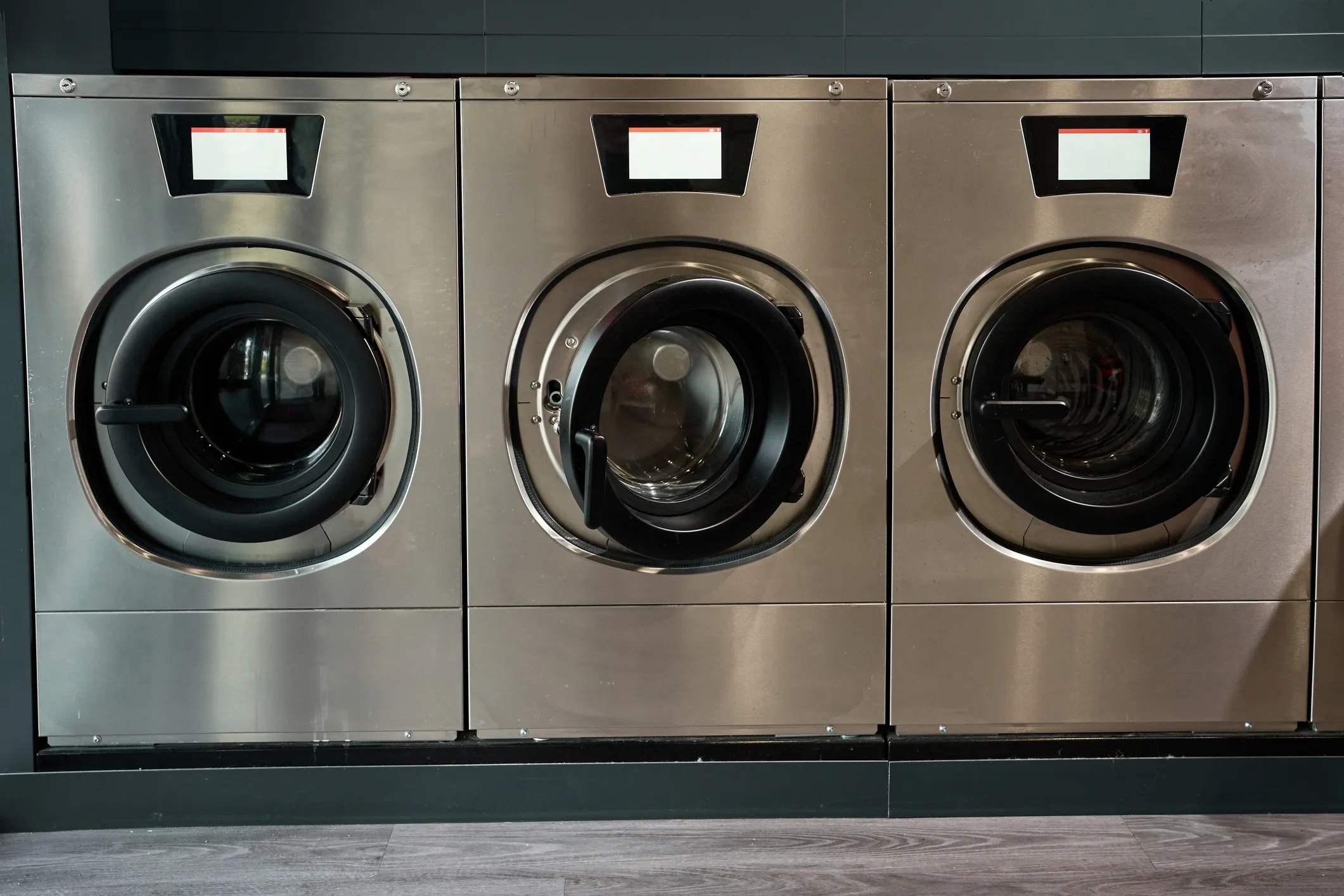 Three industrial washing machines in a row.